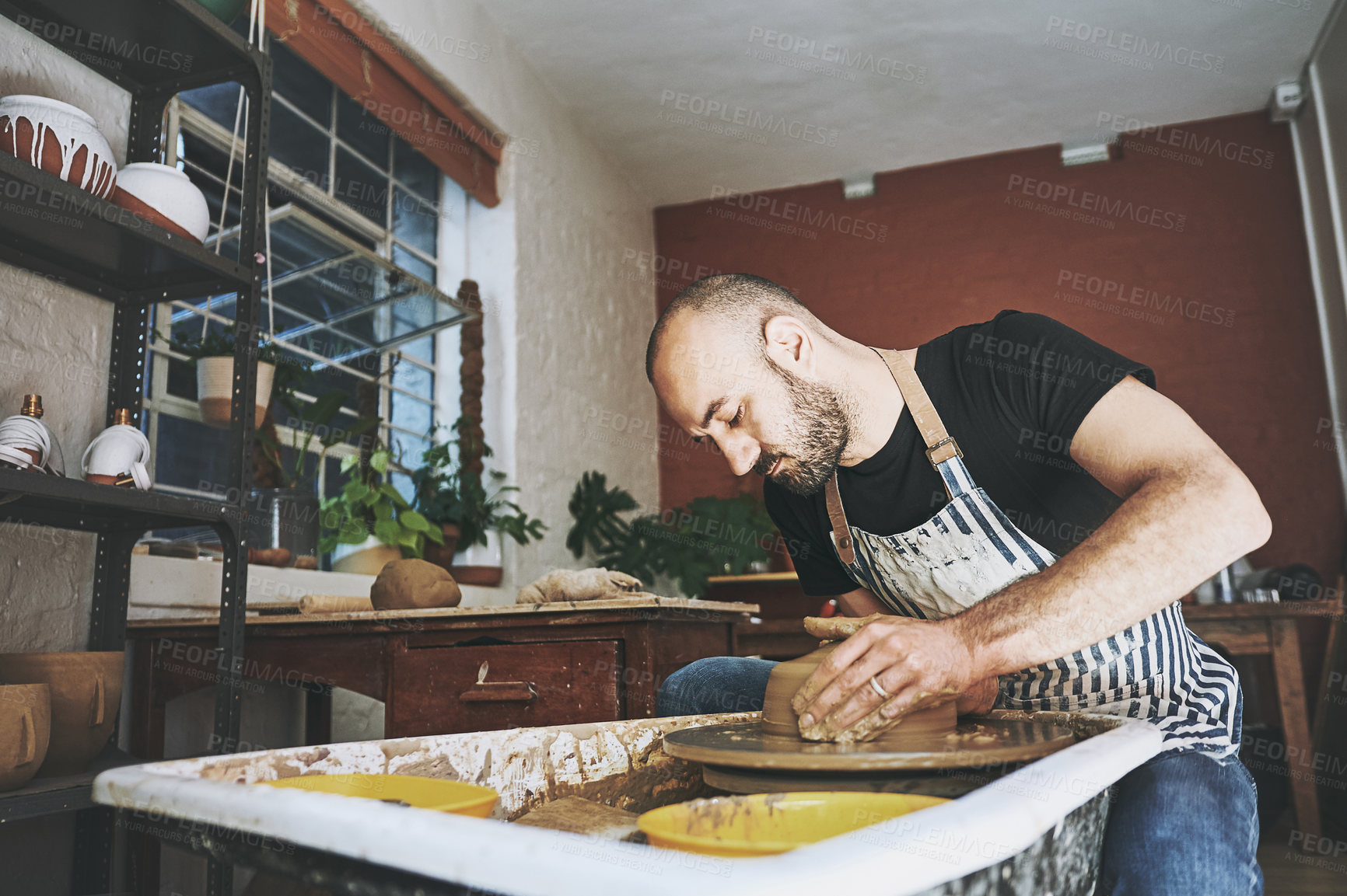 Buy stock photo Shot of a young man working with clay in a pottery studio