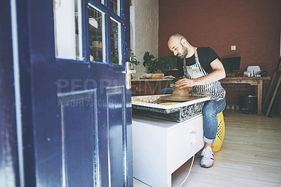 Buy stock photo Shot of a young man working with clay in a pottery studio