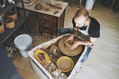 Buy stock photo Shot of a young man working with clay in a pottery studio