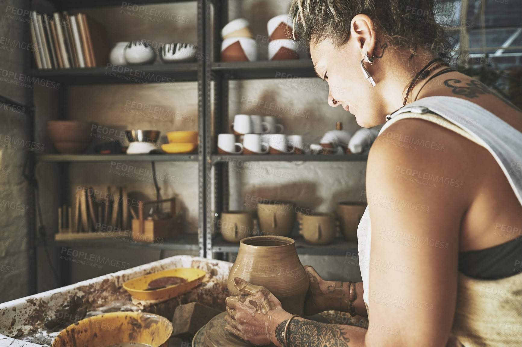 Buy stock photo Shot of a young woman working with clay in a pottery studio