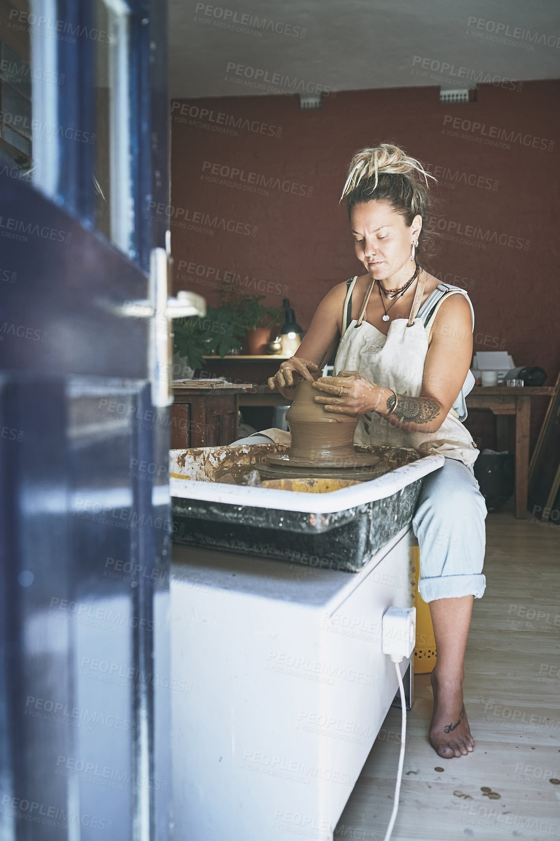 Buy stock photo Shot of a young woman working with clay in a pottery studio