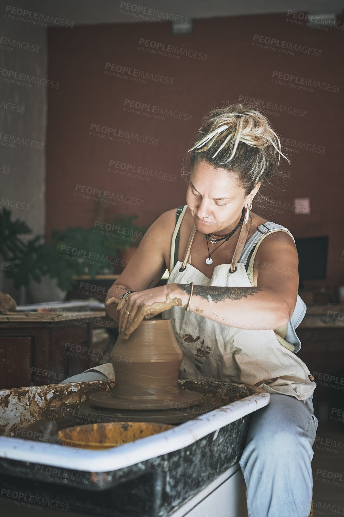 Buy stock photo Shot of a young woman working with clay in a pottery studio