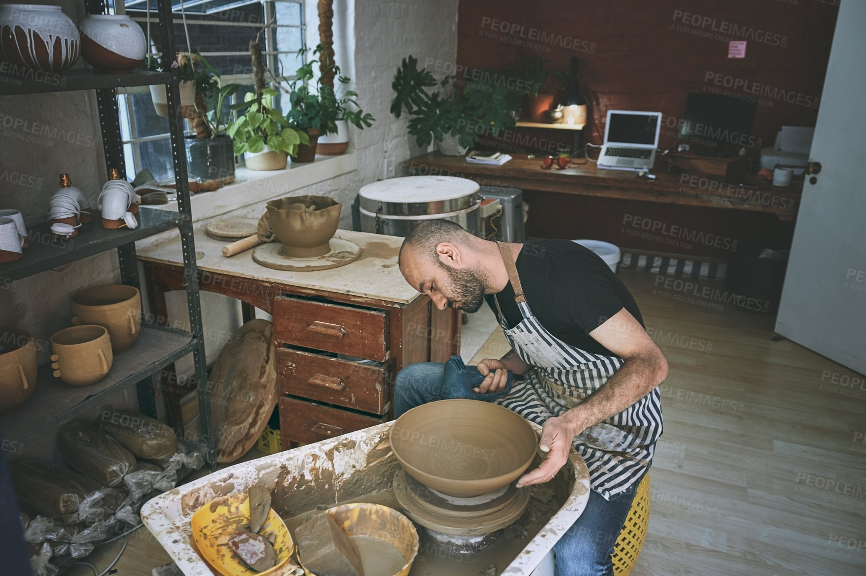 Buy stock photo Shot of a young man working with clay in a pottery studio