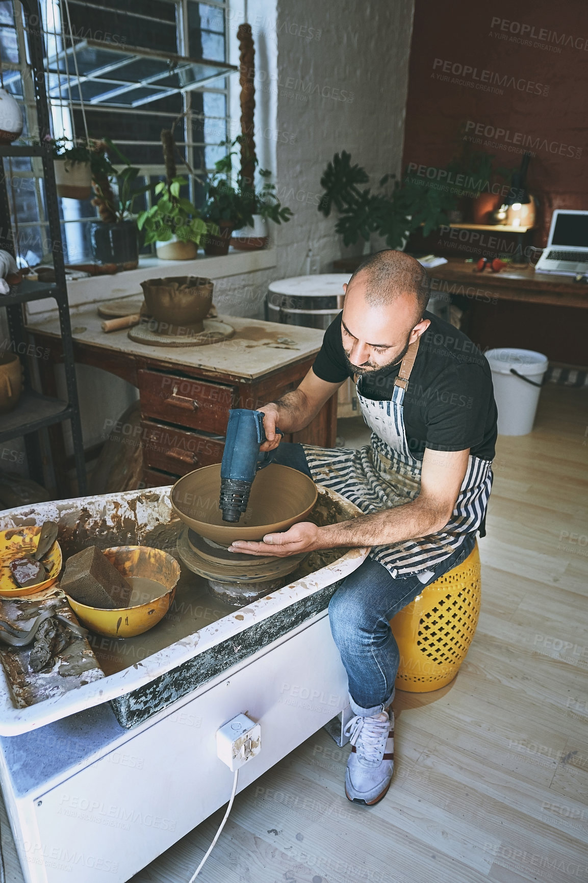 Buy stock photo Shot of a young man working with clay in a pottery studio