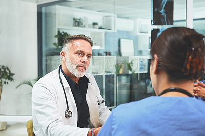 Buy stock photo Shot of a mature doctor having a discussion with a colleague in a hospital