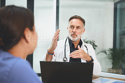 Buy stock photo Shot of a mature doctor having a discussion with a colleague in a hospital