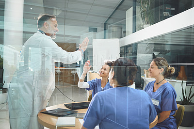 Buy stock photo Shot of doctors giving each other a high five during a meeting in a hospital
