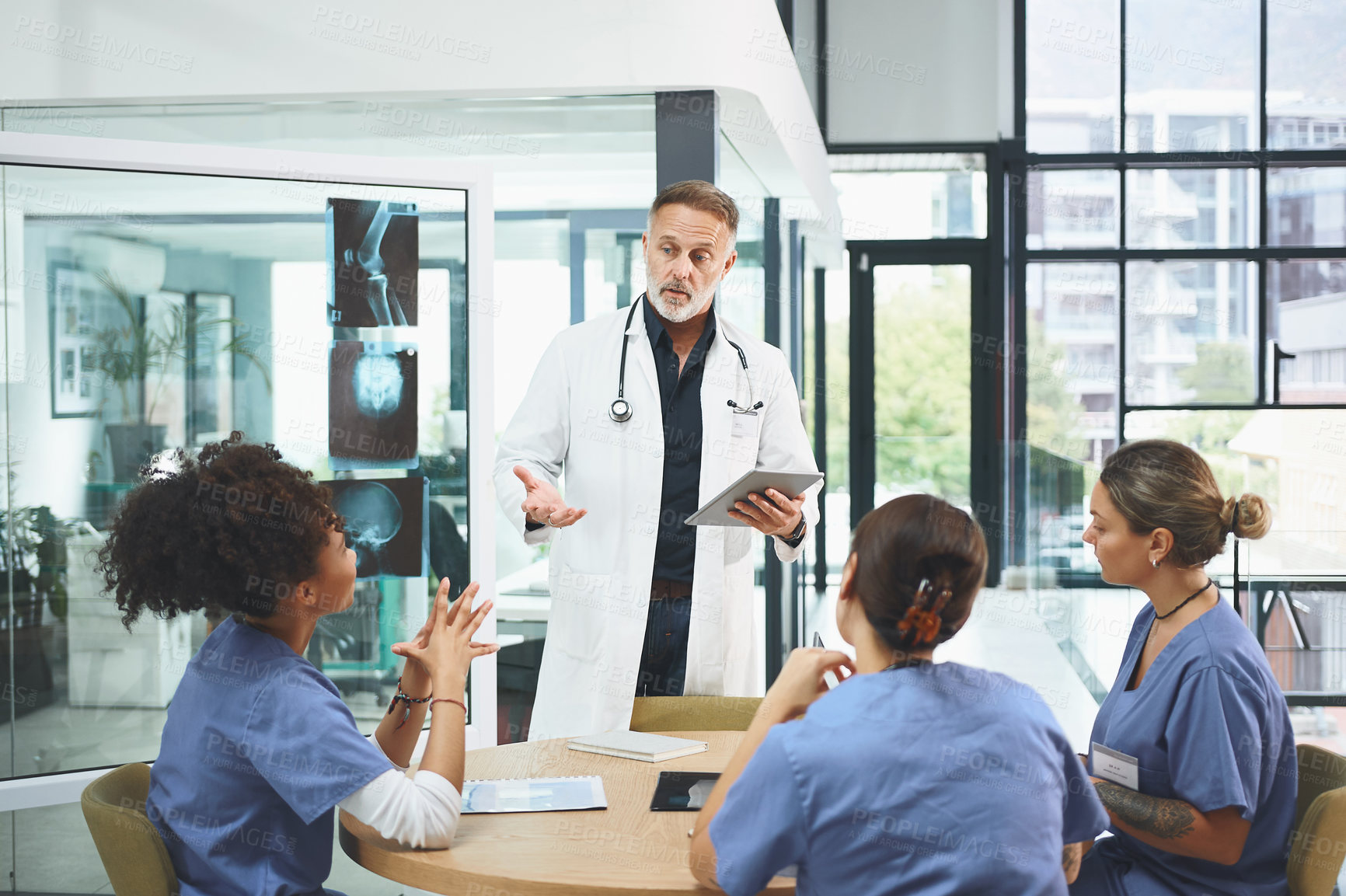 Buy stock photo Shot of a mature doctor leading a discussion with his colleagues in a hospital