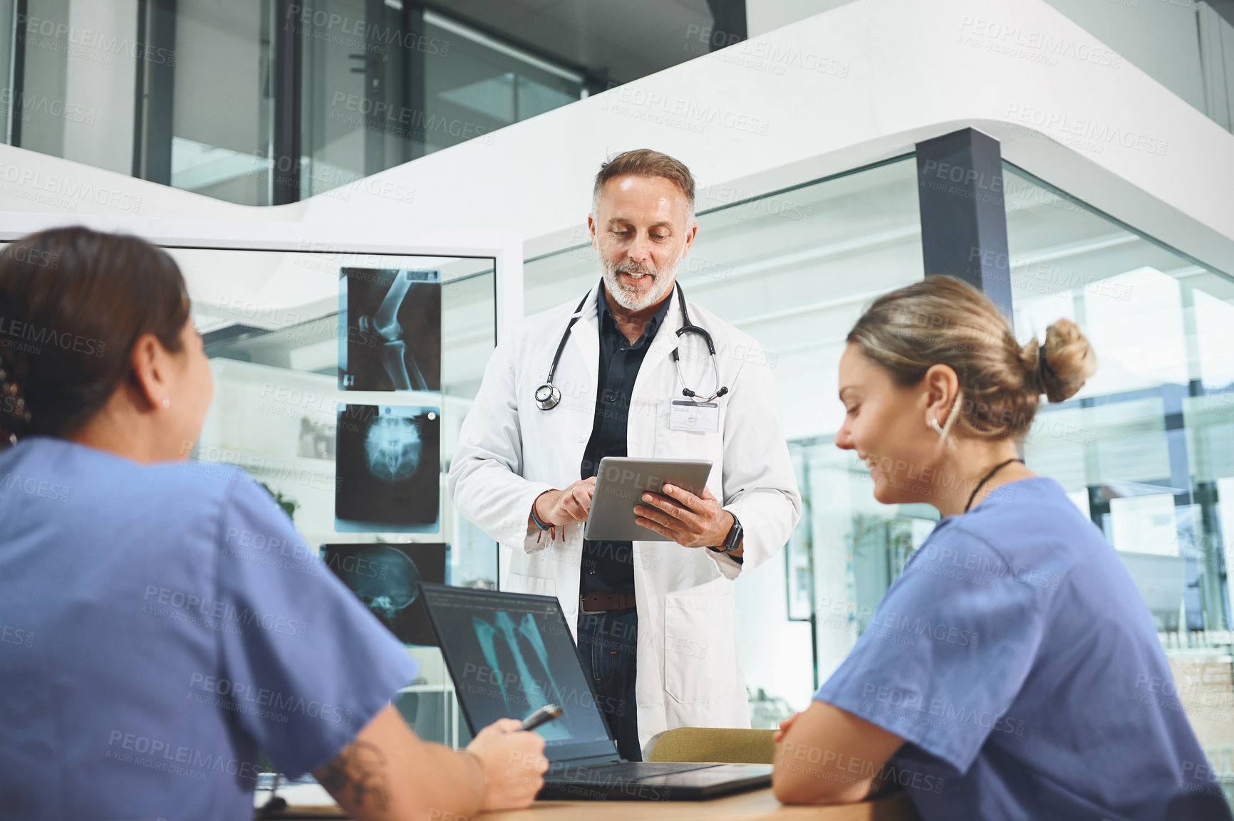 Buy stock photo Shot of a mature doctor leading a discussion with his colleagues in a hospital