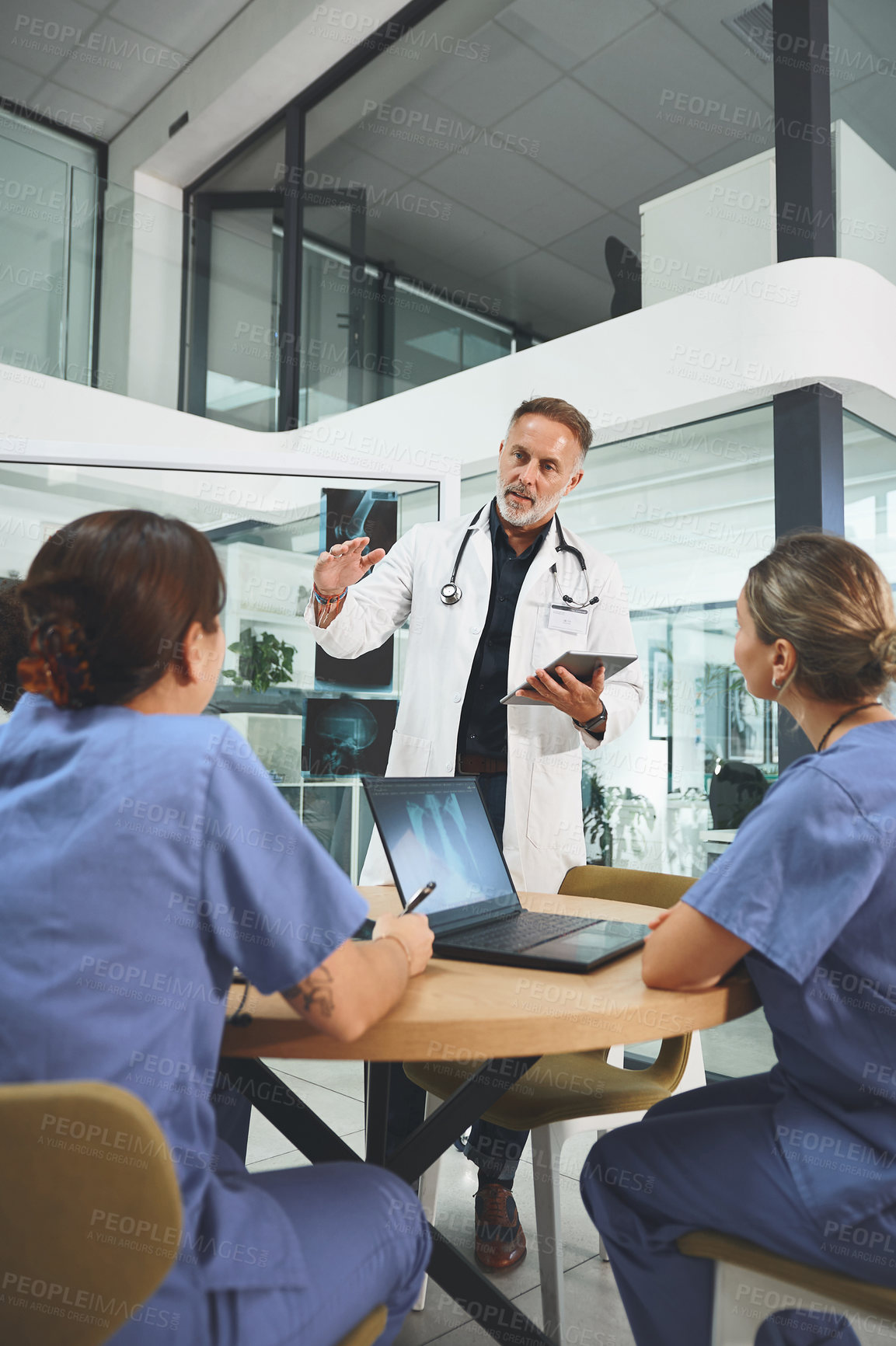 Buy stock photo Shot of a mature doctor leading a discussion with his colleagues in a hospital