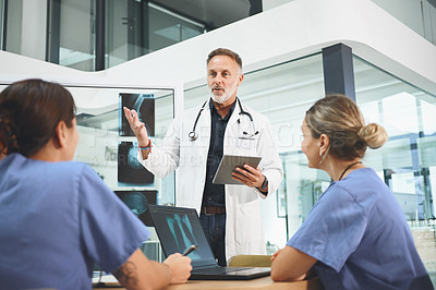 Buy stock photo Shot of a mature doctor leading a discussion with his colleagues in a hospital