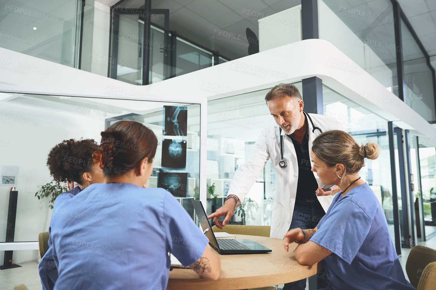 Buy stock photo Shot of a team of doctors using a laptop during a meeting in a hospital