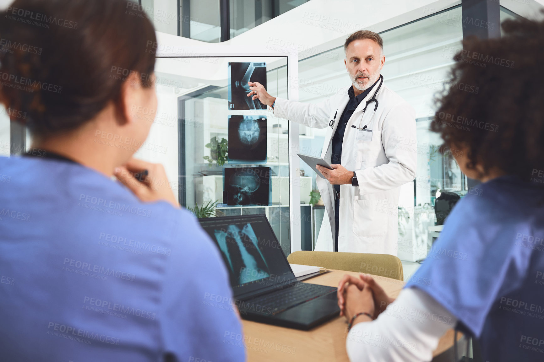 Buy stock photo Shot of a mature doctor analysing x-rays with his colleagues during a meeting in a hospital