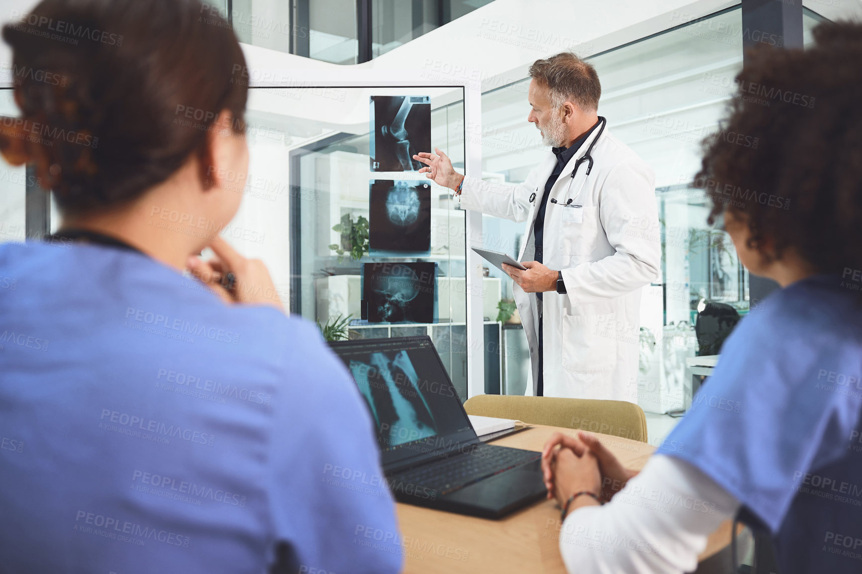 Buy stock photo Shot of a mature doctor analysing x-rays with his colleagues during a meeting in a hospital