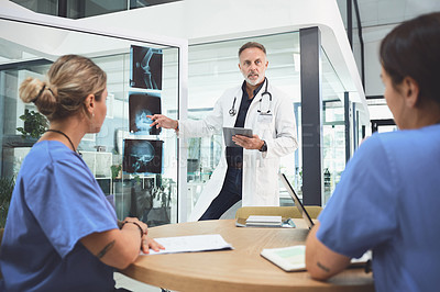 Buy stock photo Shot of a mature doctor analysing x-rays with his colleagues during a meeting in a hospital