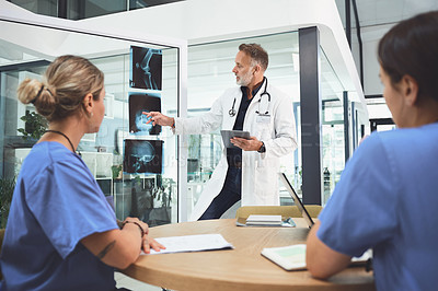 Buy stock photo Shot of a mature doctor analysing x-rays with his colleagues during a meeting in a hospital