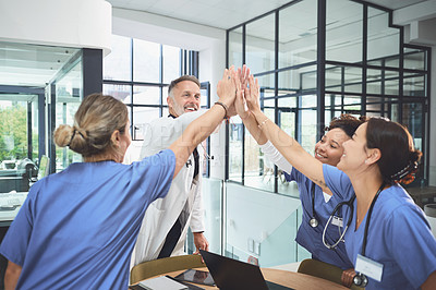 Buy stock photo Shot of a team of doctors joining their hands together in a huddle in a hospital