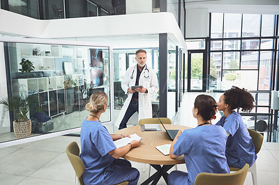 Buy stock photo Shot of a mature doctor analysing x-rays with his colleagues during a meeting in a hospital