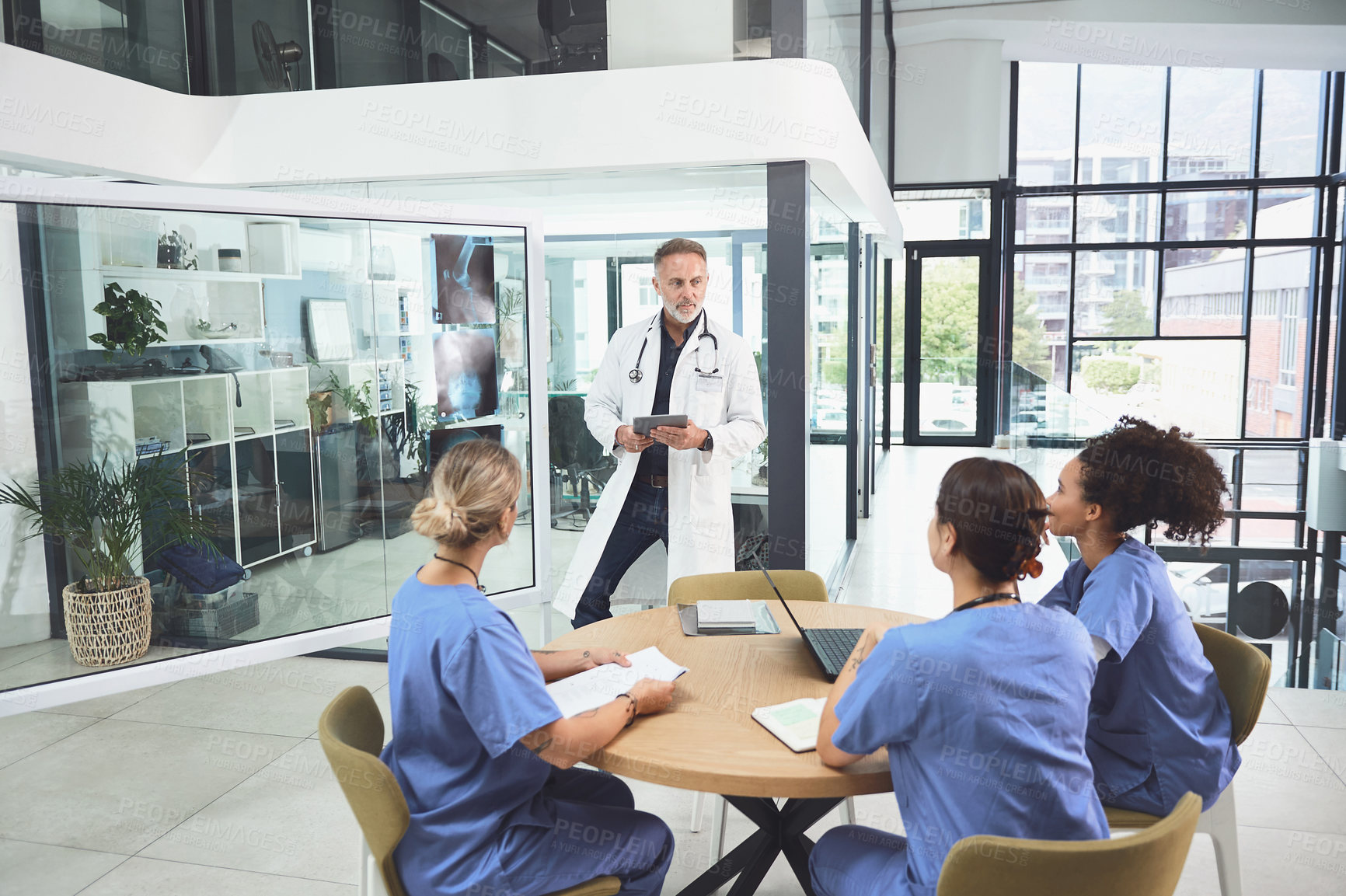 Buy stock photo Shot of a mature doctor analysing x-rays with his colleagues during a meeting in a hospital