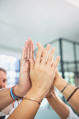 Buy stock photo Shot of a team of doctors joining their hands together in a huddle in a hospital