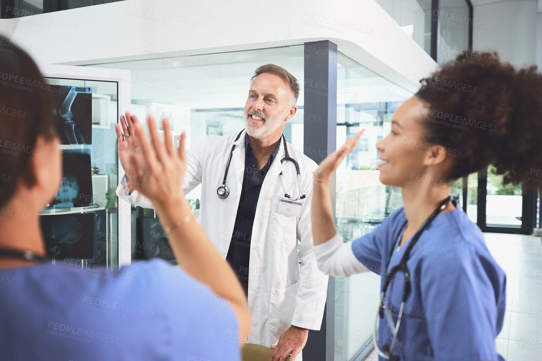 Buy stock photo Shot of a team of doctors giving each other a high five in a hospital