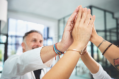 Buy stock photo Shot of a team of doctors joining their hands together in a huddle in a hospital