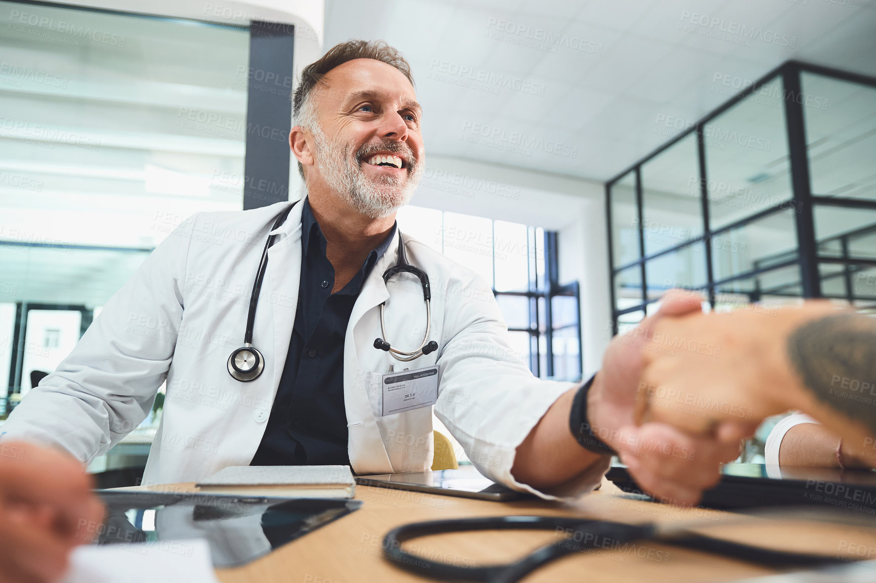 Buy stock photo Shot of doctors shaking hands during a meeting in a hospital