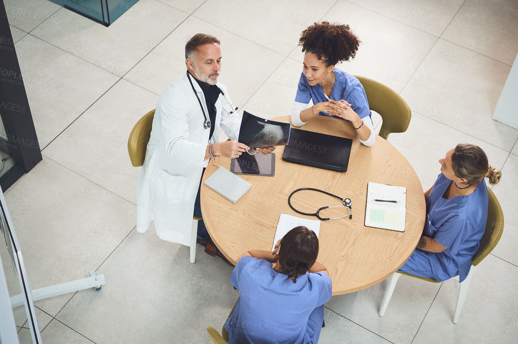 Buy stock photo Shot of a team of doctors analysing x-rays during a meeting in a hospital