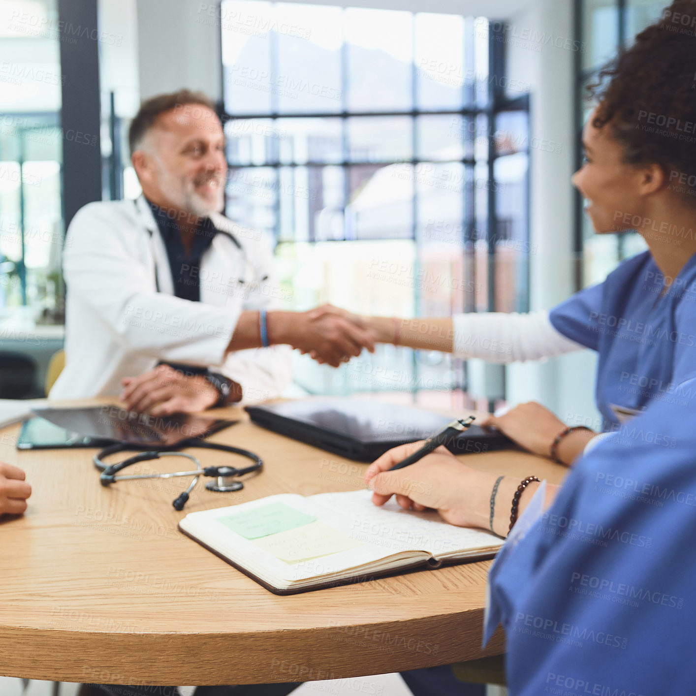 Buy stock photo Shot of doctors shaking hands during a meeting in a hospital