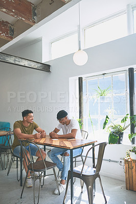 Buy stock photo Full length shot of two handsome friends sitting together and bonding in a coffeeshop during the day