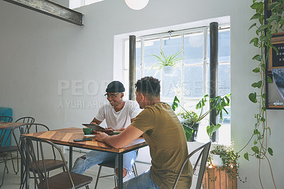 Buy stock photo Cropped shot of two handsome friends sitting together and bonding over a coffee in a cafe during the day
