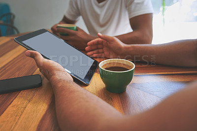 Buy stock photo Cropped shot of two unrecognizable friends sitting together and using a tablet during a discussion in a coffeeshop