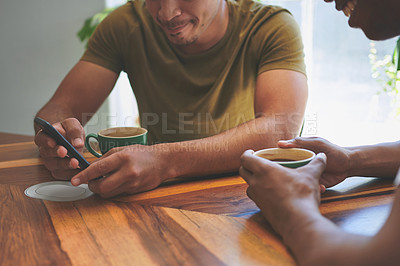 Buy stock photo Cropped shot of two unrecognizable friends sitting together and using a cellphone during a discussion in a coffeeshop