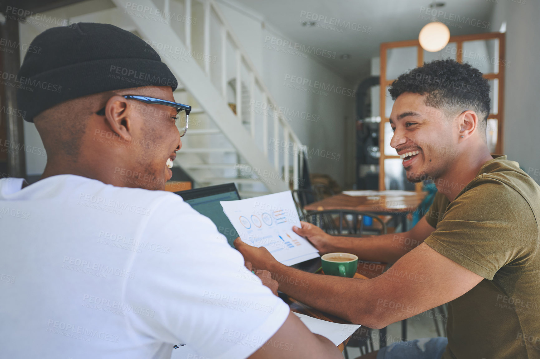 Buy stock photo Cropped shot of two handsome friends sitting together and reading through paperwork in a coffeeshop