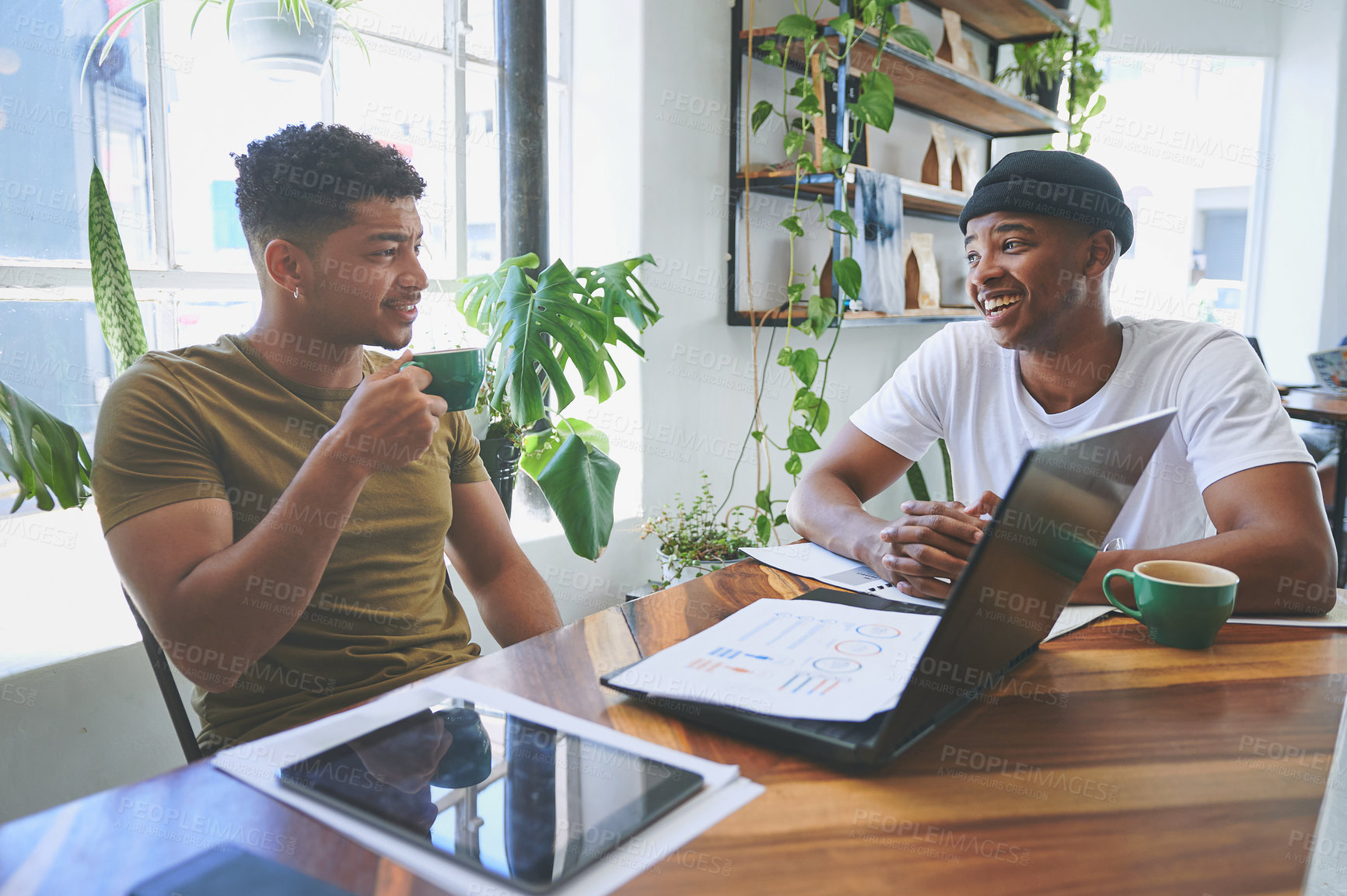 Buy stock photo Cropped shot of two handsome friends sitting together in a coffeeshop and having a discussion