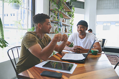 Buy stock photo Cropped shot of two handsome friends sitting together in a coffeeshop and having a discussion