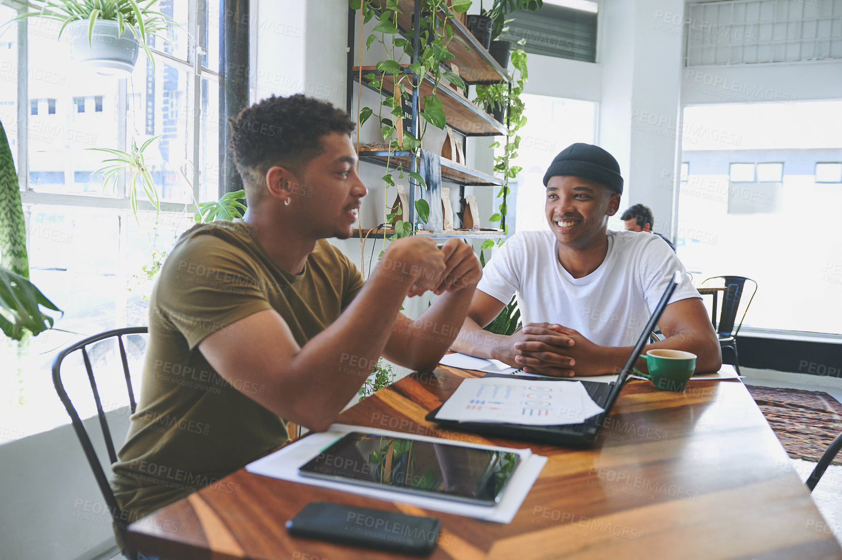 Buy stock photo Cropped shot of two handsome friends sitting together in a coffeeshop and having a discussion