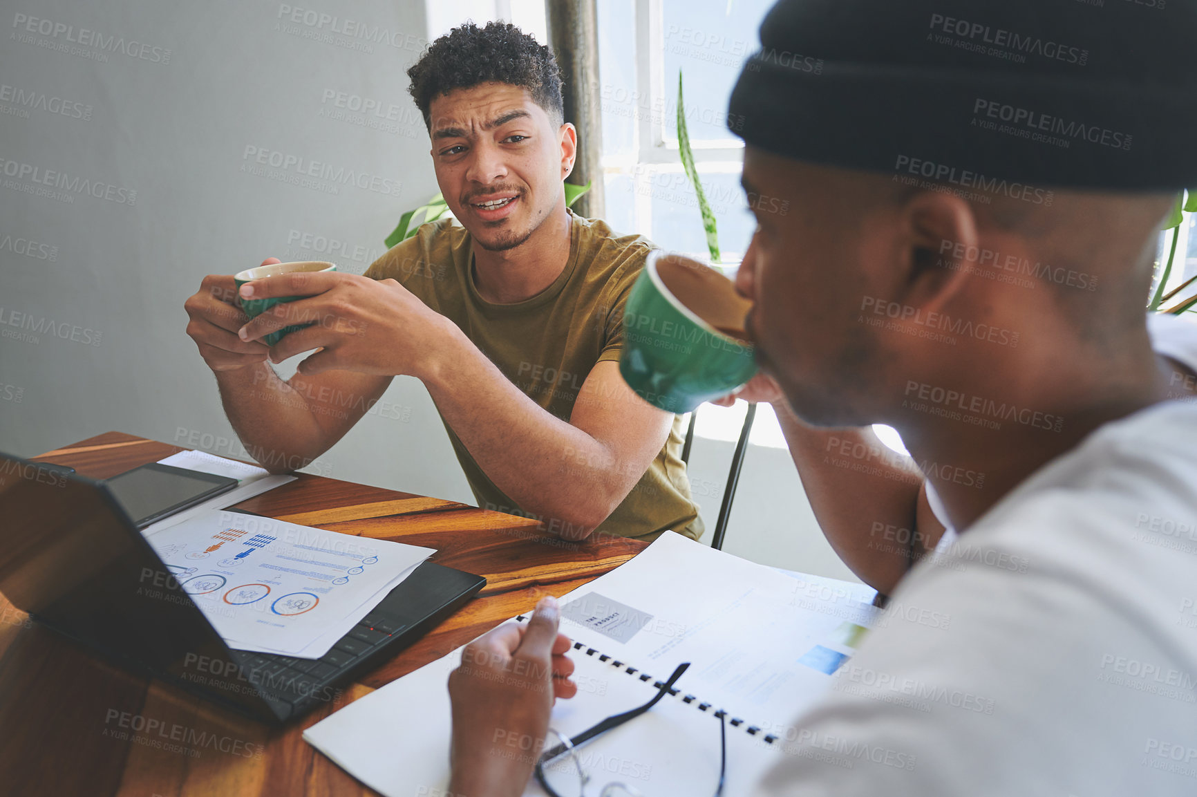 Buy stock photo Cropped shot of two handsome friends sitting together in a coffeeshop and having a discussion