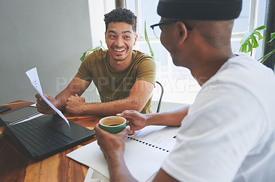 Buy stock photo Cropped shot of two handsome friends sitting together and reading through paperwork in a coffeeshop