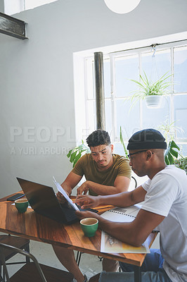 Buy stock photo Cropped shot of two handsome friends sitting together and reading through paperwork in a coffeeshop