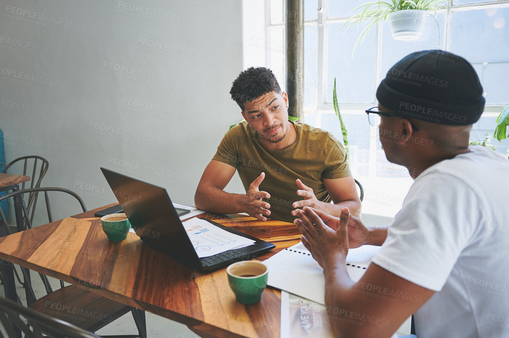 Buy stock photo Cropped shot of two handsome friends sitting together in a coffeeshop and having a discussion