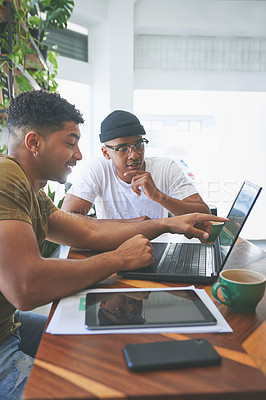 Buy stock photo Cropped shot of two handsome friends sitting together in a coffeeshop and using technology during a discussion