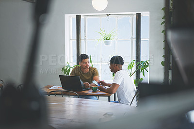 Buy stock photo Cropped shot of two handsome friends sitting together in a coffeeshop and having a discussion