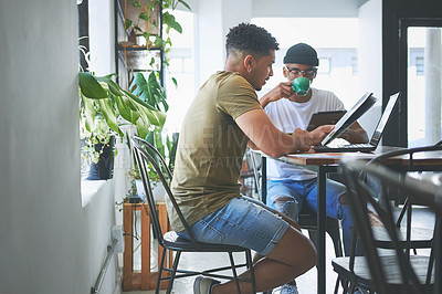 Buy stock photo Cropped shot of two handsome friends sitting together and reading through paperwork in a coffeeshop