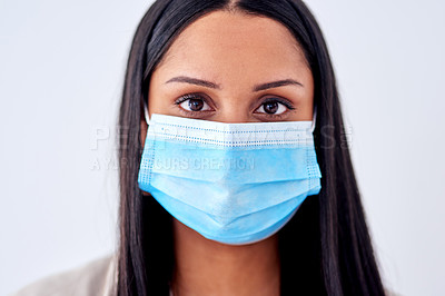 Buy stock photo Studio portrait of a young woman wearing a face mask against a white background