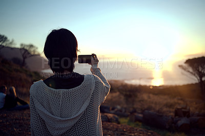 Buy stock photo Hiking, photography and woman with phone at sunset sky, nature and mountain to relax on holiday adventure. Smartphone, trekking and person with view of island, ocean and memory on vacation from back