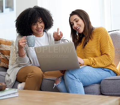 Buy stock photo Shot of two young women using a laptop together at home