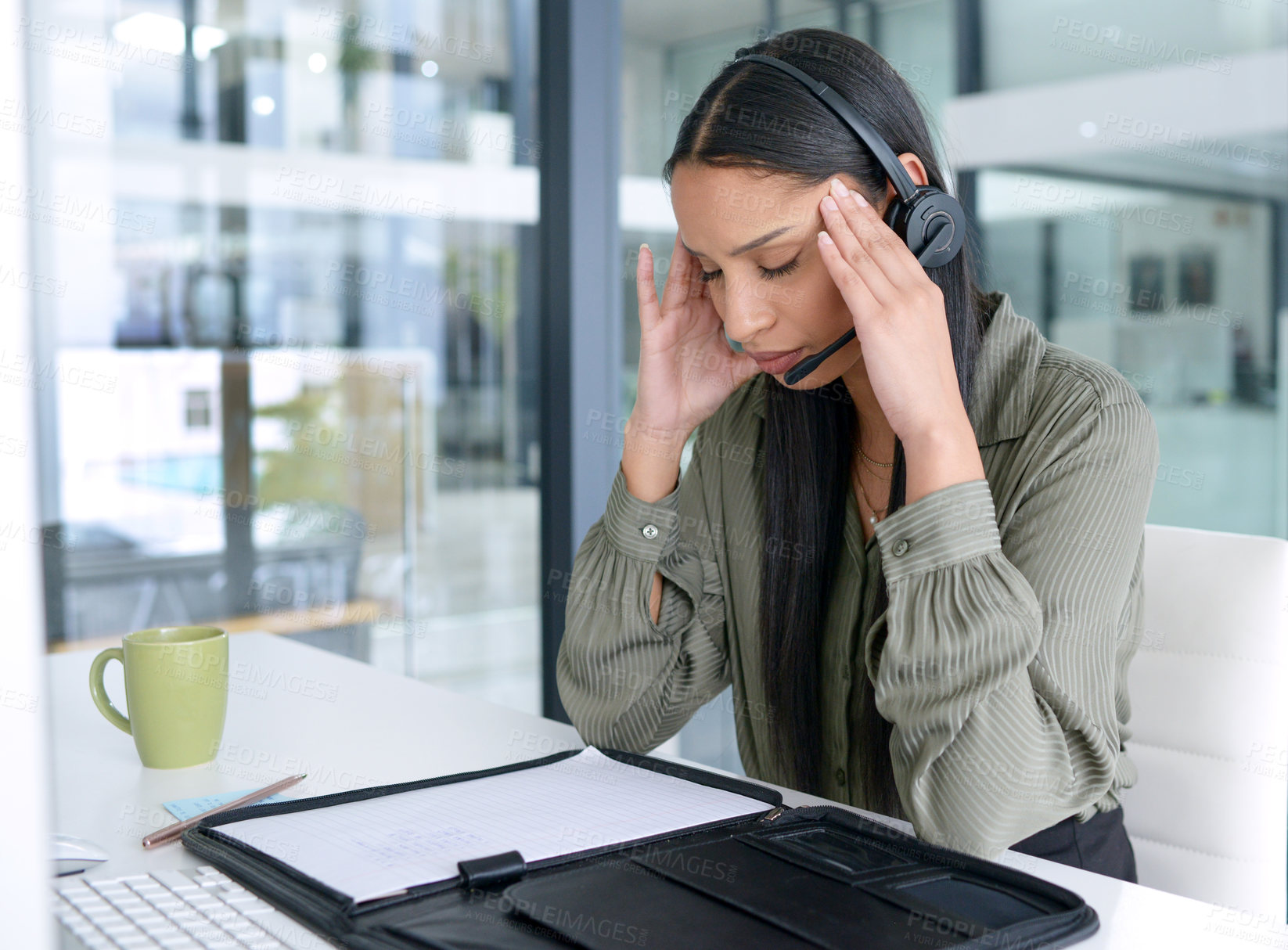 Buy stock photo Shot of a young call centre agent looking stressed out while working in an office