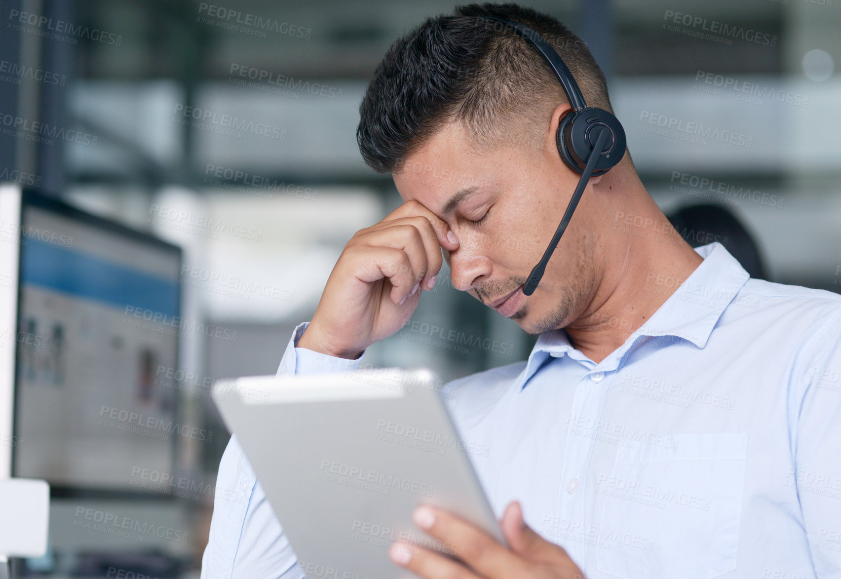 Buy stock photo Shot of a young call centre agent looking stressed out while working in an office