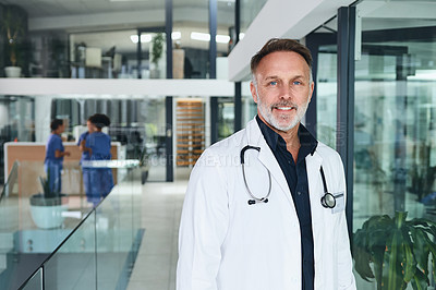 Buy stock photo Cropped portrait of a handsome mature doctor standing in the clinic during the day